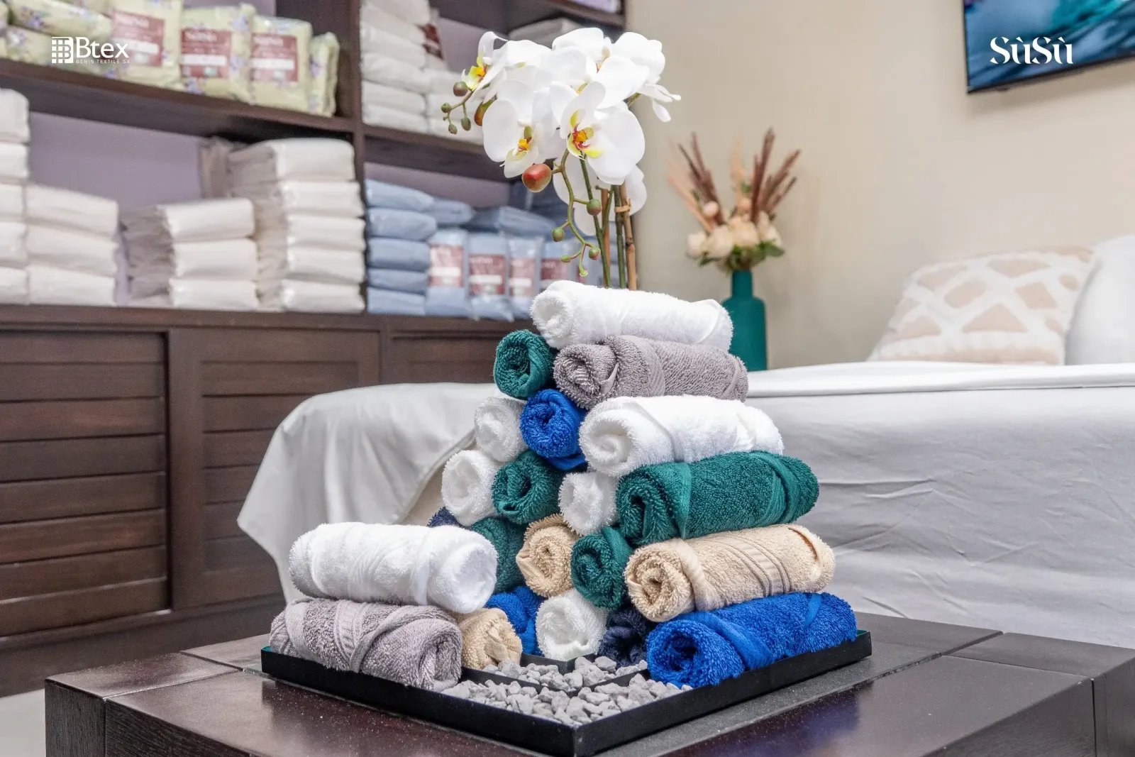 Rolled and stacked Sùsù towels, with a white orchid